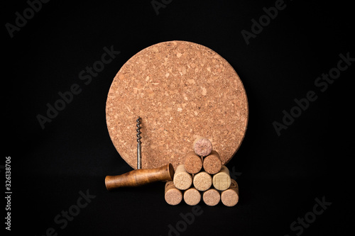 Round kitchen cork stand, pyramid of wine corks and old corkscrew on black fabric