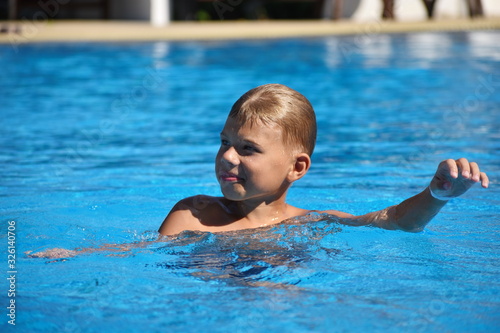 Child boy swimmer. The boy in the pool at the hotel. Sports holiday with children at the resort. © Victoria