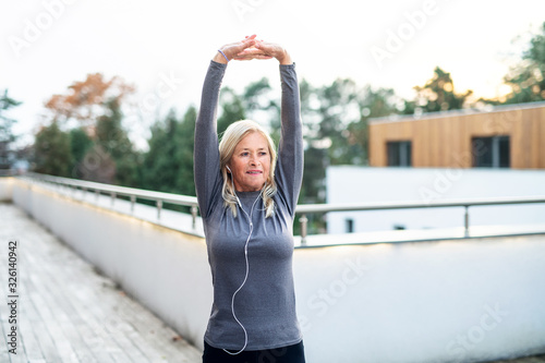 A senior woman doing exercise outdoors, stretching. photo