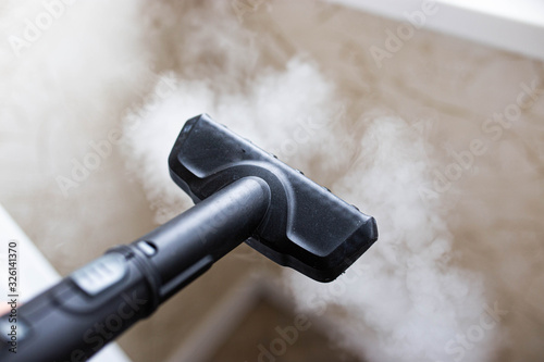 steam cleaner for cleaning the house, steam erupts from the brush. photo