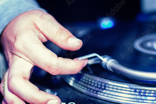 DJ turnablist positioning needle on vinyl record closeup photo