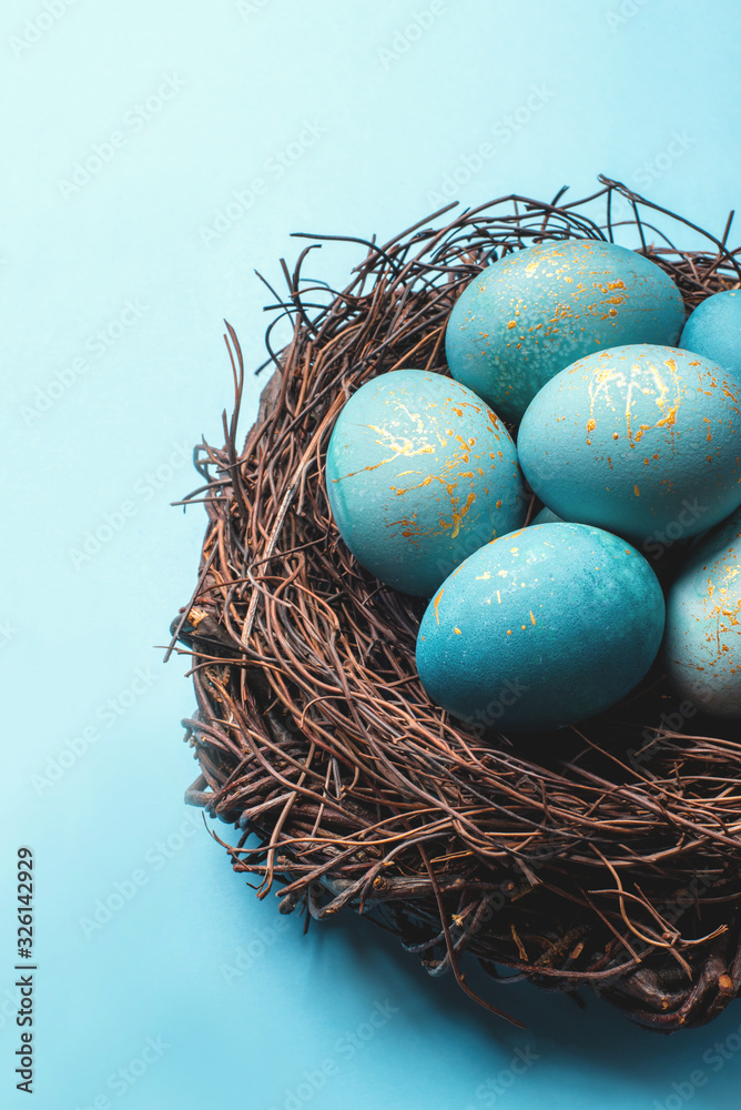 Fototapeta premium Easter eggs in nest on blue background. Close up.