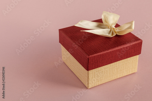 Gift box with a bow on a pink background. Selective focus. Space for text.