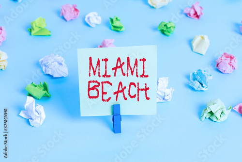 Word writing text Miami Beach. Business photo showcasing the coastal resort city in MiamiDade County of Florida Colored crumpled papers empty reminder blue floor background clothespin photo