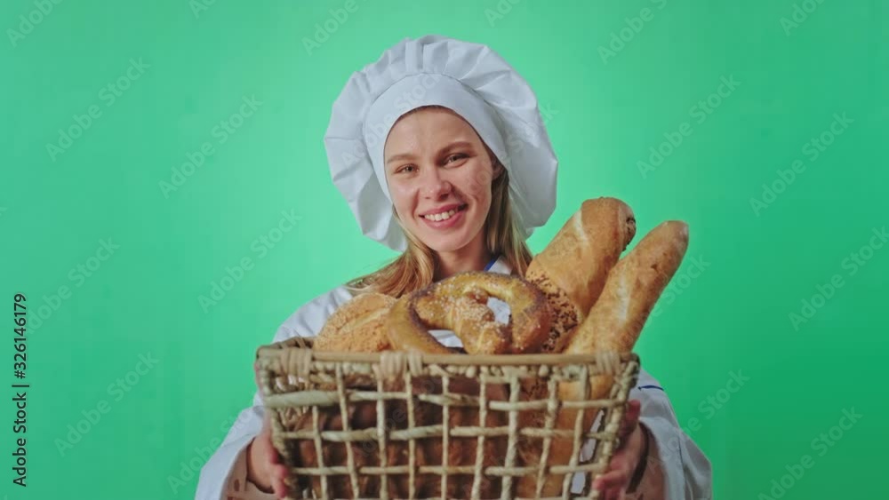 Pretty female baker smelling with love fresh bread froth the basket in front of the camera inside of a green studio chroma key Pretty female baker smelling with love fresh bread froth the basket in front of the camera inside of a green studio chroma key