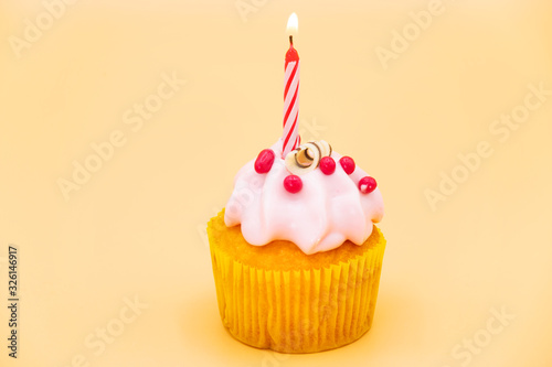 Tasty birthday cupcake with candle  on orange background .