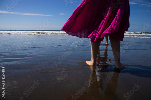 Woman walks on the beach during the day.