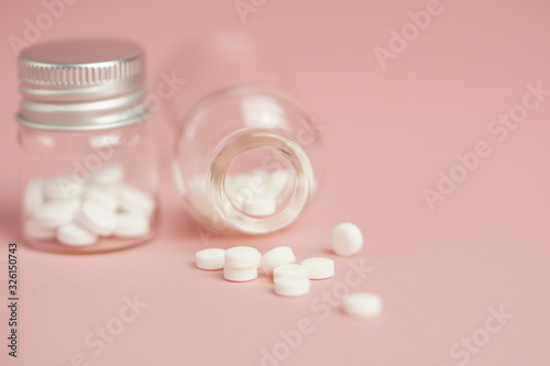 White medical pills in glass bottles,on pink background. Closeup photo of medical preparations with copy spaes.