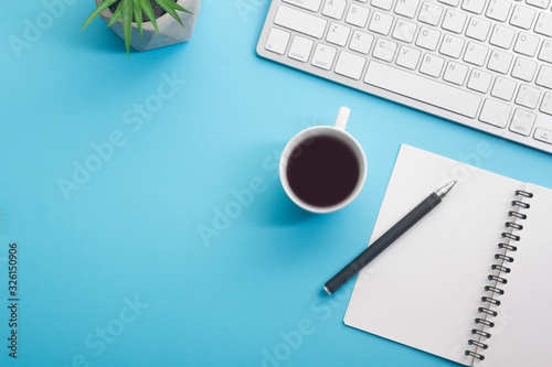 Blue desk office with laptop  smartphone and other work supplies with cup of coffee. Top view with copy space for input the text. Designer workspace on desk table essential elements on flat lay