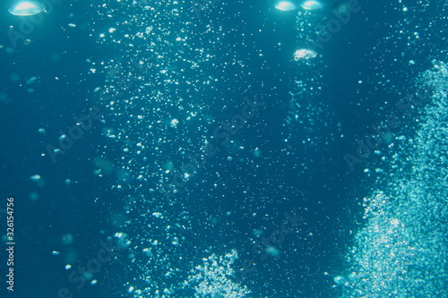 Blue ocean waves from underwater with bubbles. Light rays shining through. Great for backgrounds.