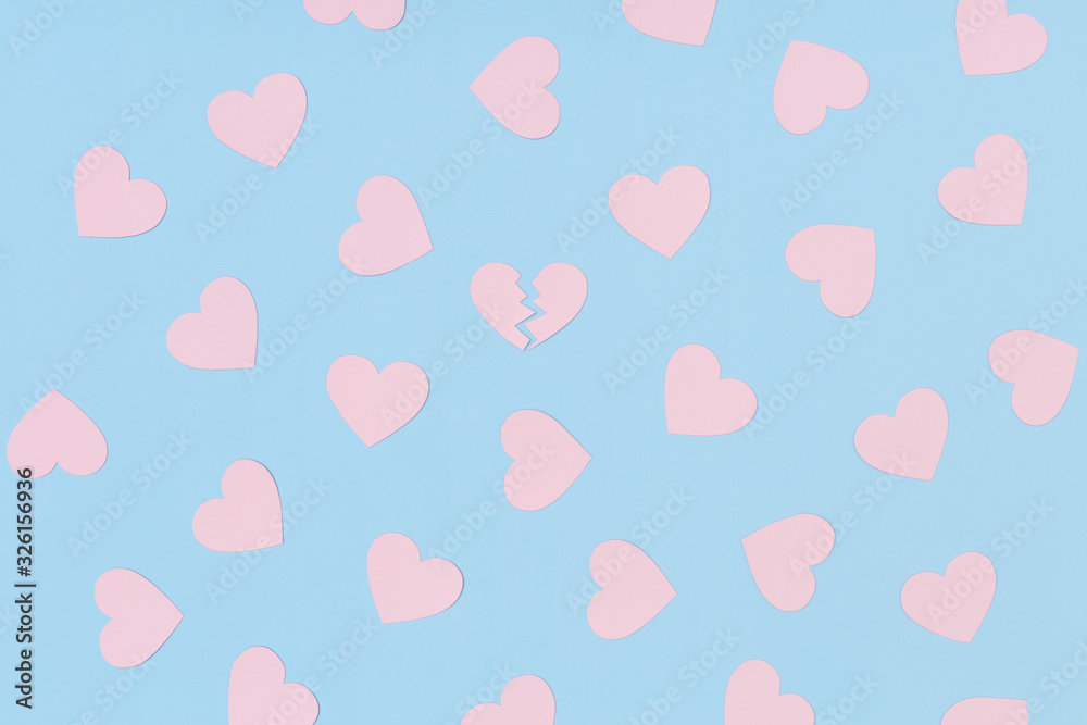 Pattern of pink paper hearts and one broken heart among them on the blue background