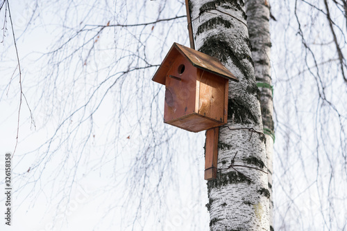 Wooden birdhouse on a tree in winter. © delobol