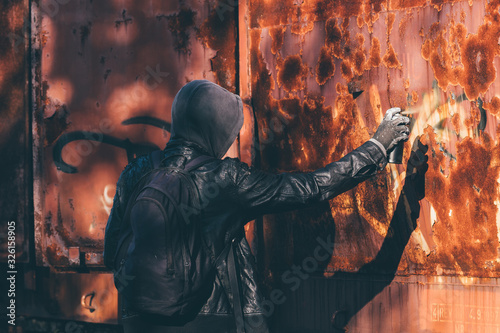 Homeless man spray painting old train wagon with aerosol can
