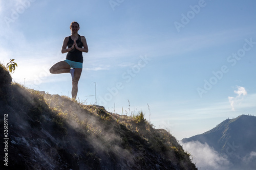 Woman practicing yoga on a volcano in Bali