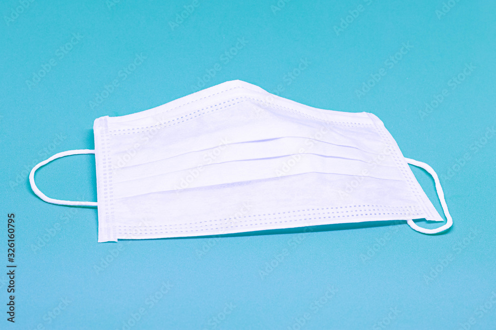Medical surgical mask on a green background, isolated, coronavirus concept (COVID-19), close-up Medical surgical mask on a green background, isolated, coronavirus concept (COVID-19), close-up