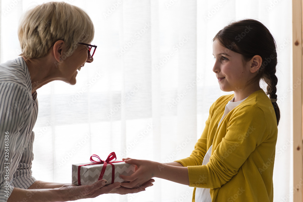 Granddaughter gives a gift to her grandmother Granddaughter gives a gift to her grandmother