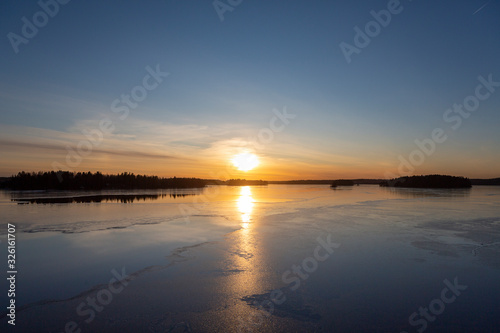 Amazing winter sunset in Finland. Cold afternoon in February, reflecting water and icy surface. Wintry landscape wallpaper, copy space. © Jne Valokuvaus