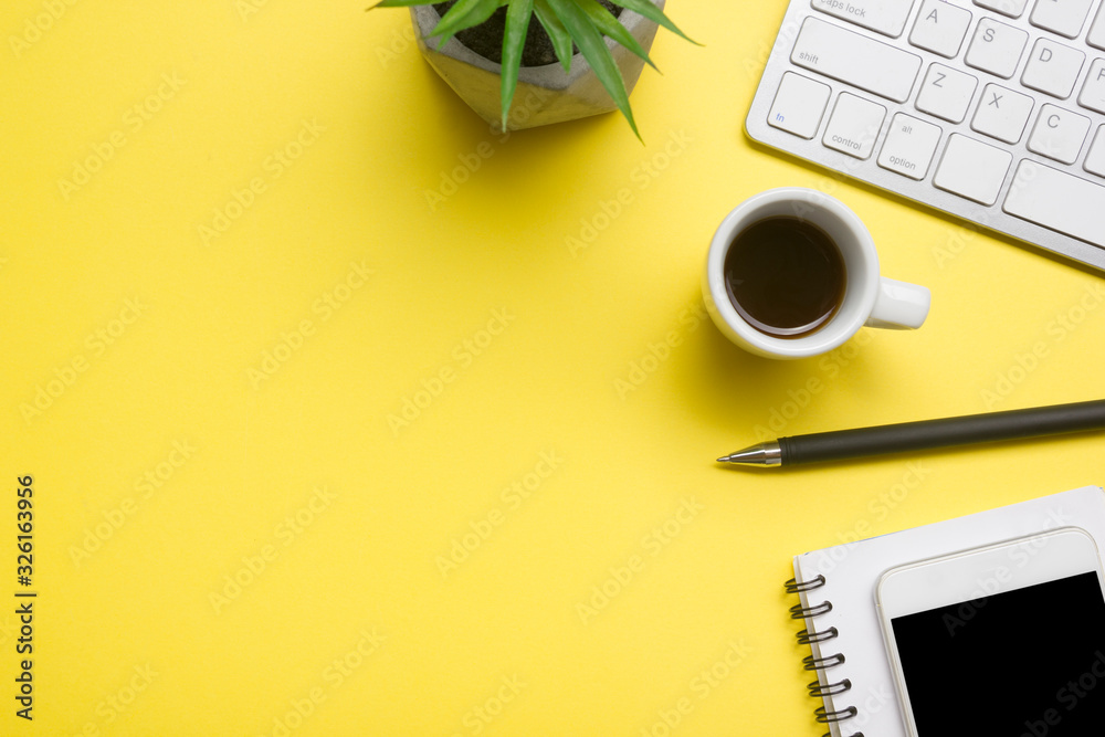 Yellow desk office with laptop, smartphone and other work supplies with cup of coffee. Top view with copy space for input the text. Designer workspace on desk table essential elements on flat lay