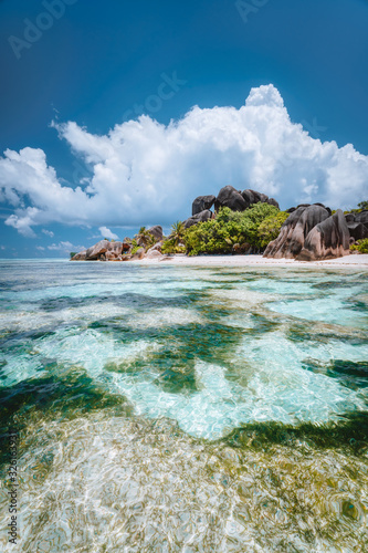 La Digue island, Seychelles. Famous paradise beach Anse Source d'Argent with shallow blue lagoon, granite boulders and white clouds