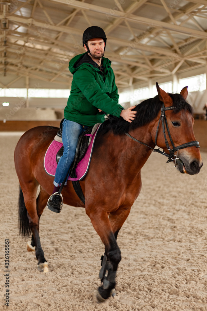man jockey sitting on horse, horseback training on manege, lesson for jockey in equestrian school or club, pet animal man jockey sitting on horse, horseback training on manege, lesson for jockey in equestrian school or club, pet animal