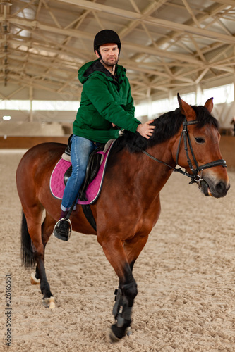 man jockey sitting on horse, horseback training on manege, lesson for jockey in equestrian school or club, pet animal © Stockgurulab