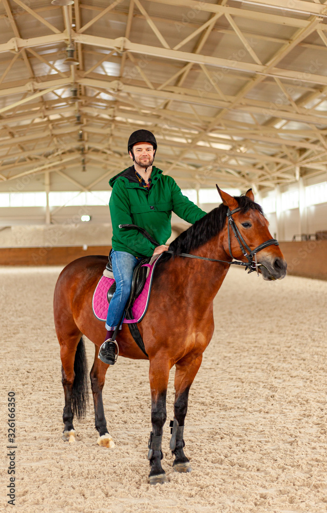 man jockey sitting on horse, horseback training on manege, lesson for jockey in equestrian school or club, pet animal man jockey sitting on horse, horseback training on manege, lesson for jockey in equestrian school or club, pet animal