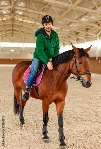 man jockey sitting on horse, horseback training on manege, lesson for jockey in equestrian school or club, pet animal © Stockgurulab