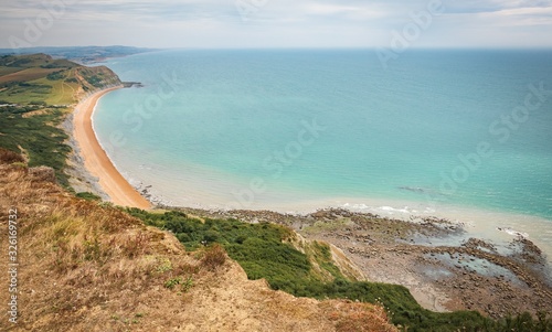 Fototapeta Naklejka Na Ścianę i Meble -  Green fields on a hill with the sea English Channel and English countryside in the background. Golden Cap on jurassic coast in Dorset, UK.