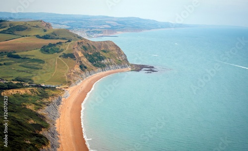 Green fields on a hill with the sea English Channel and English countryside in the background. Golden Cap on jurassic coast in Dorset, UK.