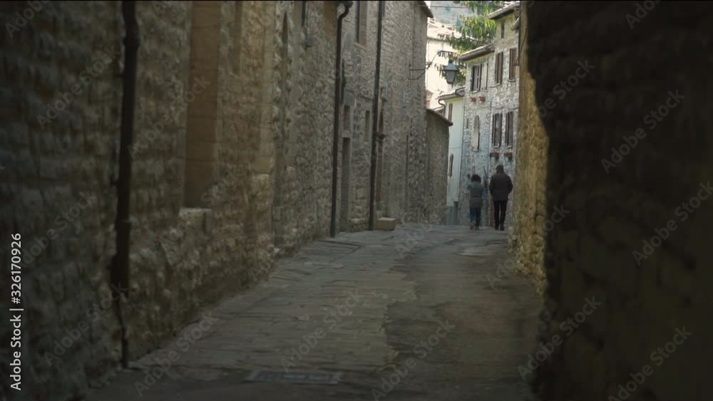 Two People Walking in a Shady Alley