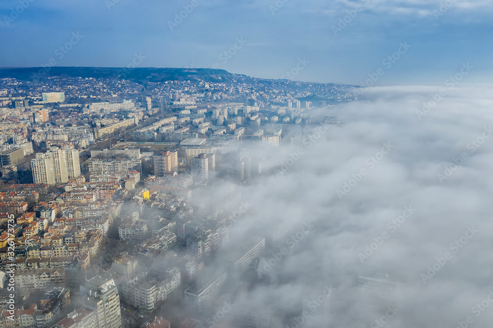 Obraz premium Fog clouds coming over the city from sea, aerial landscape from a drone. View from above.