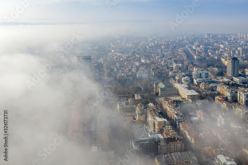 Fog clouds coming over the city from sea, aerial landscape from a drone. View from above.