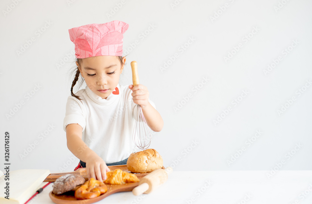 Asian little chef girl show action of happy and fun with bread and cake cooking with white background.