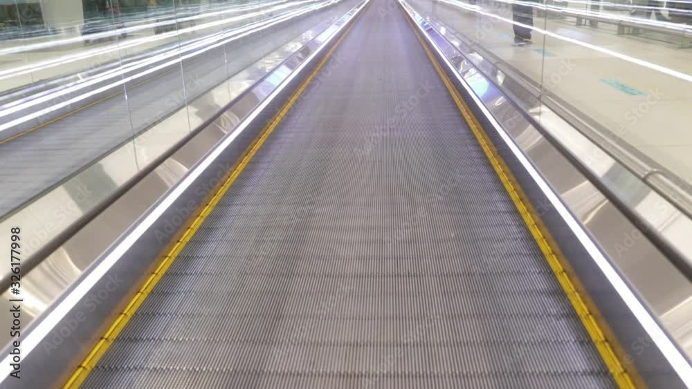 girl with a pink suitcase walks on a horizontal escalator