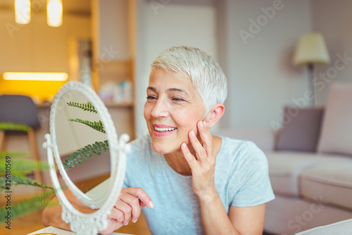 Foto Happy mature woman admiring herself in the mirror