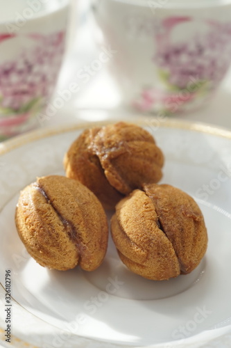 Cookies in the form of walnuts on a white saucer. Background two
