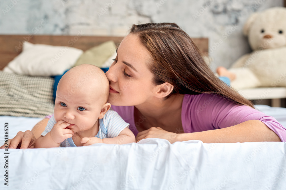 Young adult mom kissing cute little new born baby Young adult mom kissing cute little new born baby
