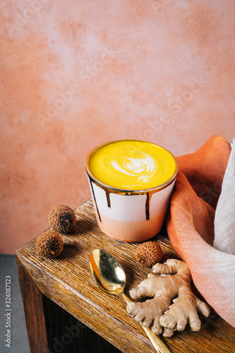 Golden milk latte in pink and gold cup with tumeric and ginger