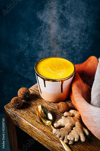 Golden milk latte in pink and gold cup with tumeric and ginger