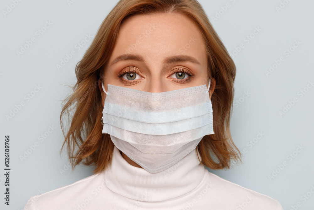 Studio portrait of woman wearing face medical mask, looking at camera, isolated on blue background, close up. Flu epidemic, dust allergy, protection against virus. Covid-19, coronavirus. Studio portrait of woman wearing face medical mask, looking at camera, isolated on blue background, close up. Flu epidemic, dust allergy, protection against virus. Covid-19, coronavirus.