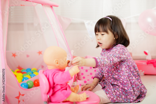 toddler girl pretend play baby care at home against white background