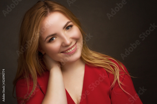 a blonde girl with an overweight plus size, in a red overallposing on a dark Studio background