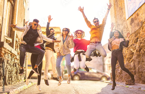 Multi-ethnic group of young people having fun together outdoors in urban background. group of friends jumping together in the street on a sunny day. Togetherness concept.