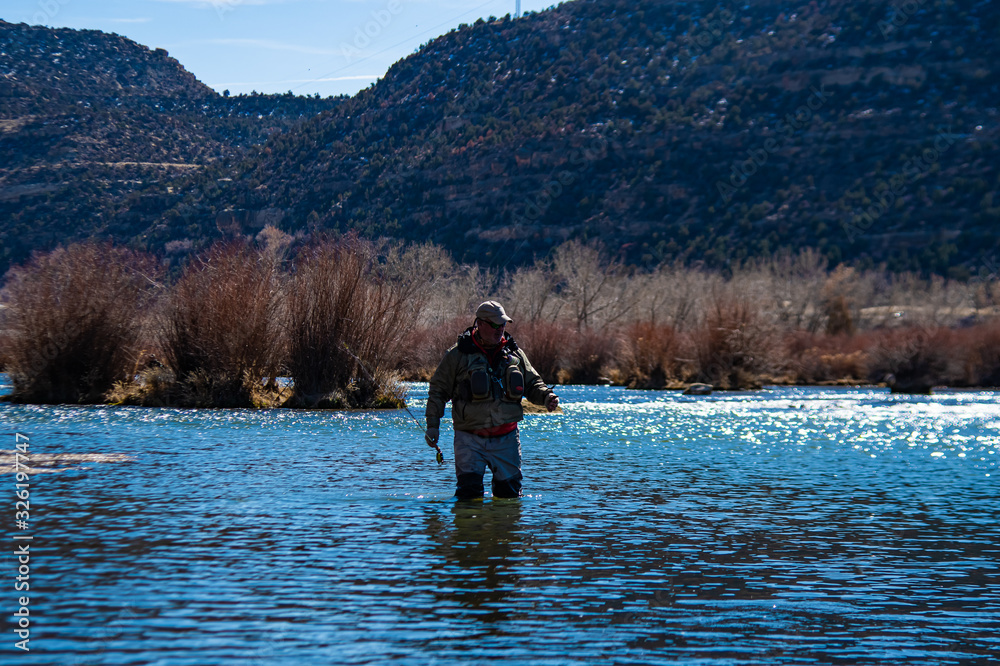 A man fly fishing on the San Jaun river in the winter.