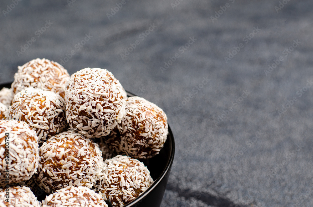 Energy balls from dates, peanuts, honey, oats in a black bowl on a dark background, copy space, flat lay Energy balls from dates, peanuts, honey, oats in a black bowl on a dark background, copy space, flat lay