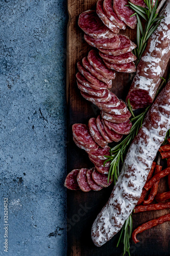 Fuet, a traditional Spanish sausage with rosemary. Slice sausages. Rosemary. Top view. Free space for your text.