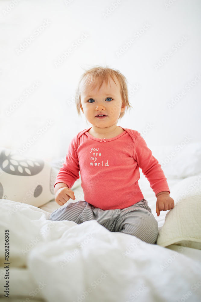 Adorable toddler girl sitting on bed Adorable toddler girl sitting on bed
