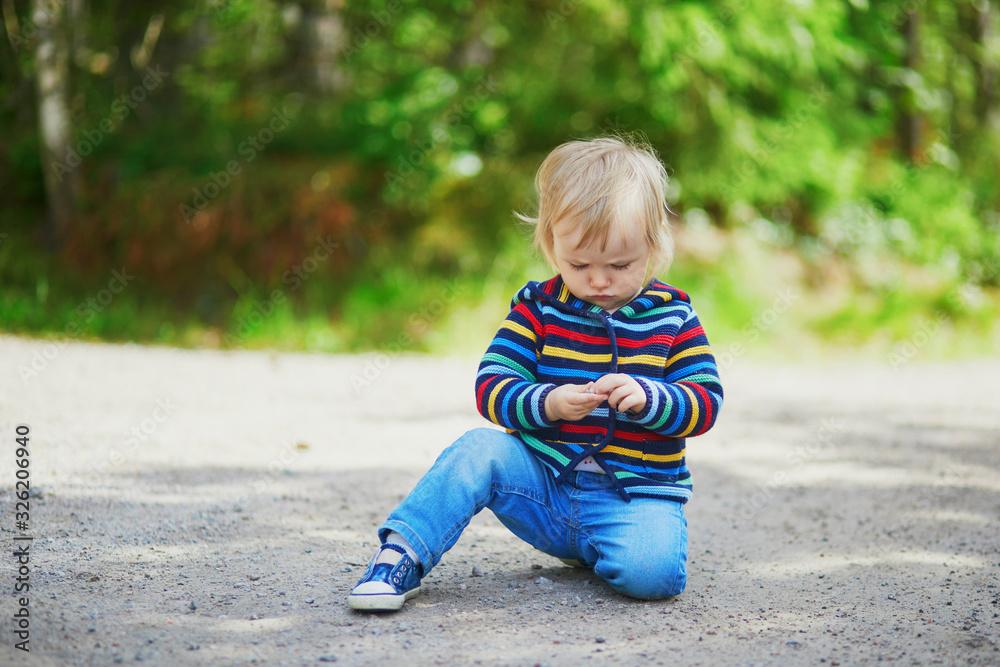 Adorable baby girl in the forest, sitting on the ground Adorable baby girl in the forest, sitting on the ground