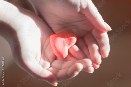 Fototapeta Naklejka Na Ścianę i Meble -   child's hands holding red heart, health care, love and support, organ donation, family insurance and CSR concept, world heart day, world health day, National Organ Donor Day