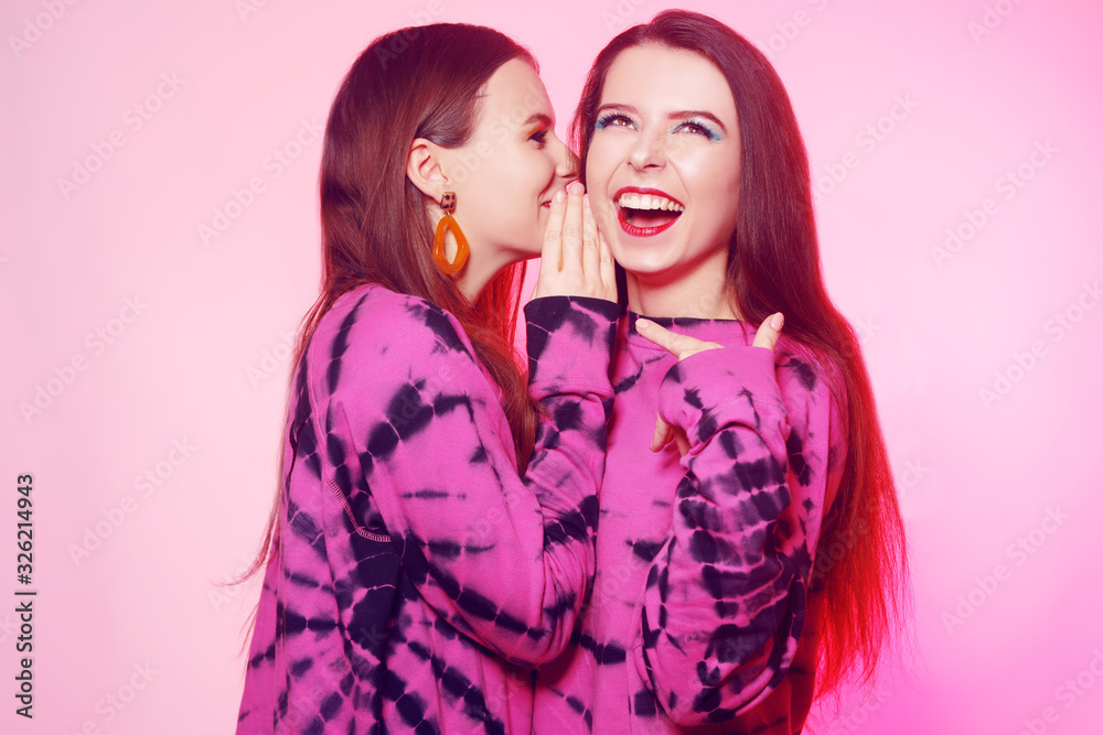 2 girls in the same things with bright makeup. Brunette girls, sisters, girlfriends, twins gossip, discuss, laugh. Women's power, March 8, Women's Day.